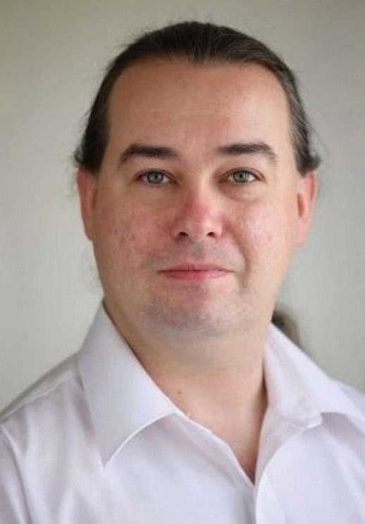 Portrait photograph of alexander hanysz in a white business shirt.