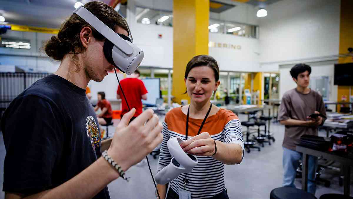 Cael gallagher educating a first-year earth science student using virtual reality equipment designed during her phd.