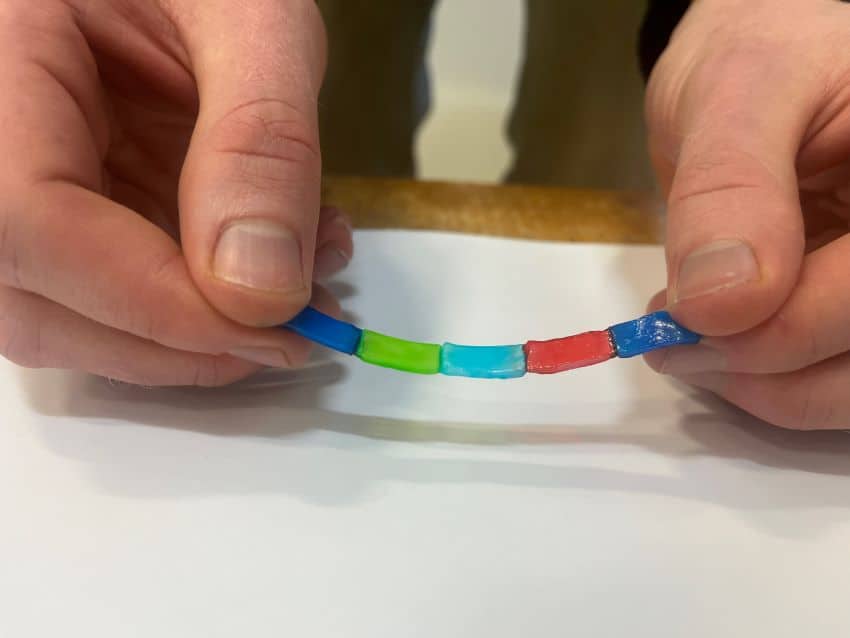 Chain of coloured jelly like batteries held in between hands
