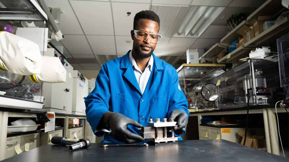Battery researcher in blue lab coat assembling test flow battery