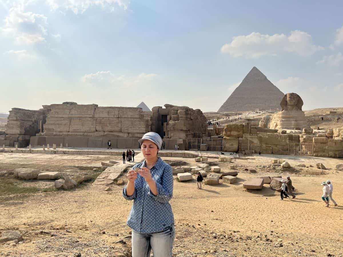 A woman stands in front of pyramids in giza, egypt