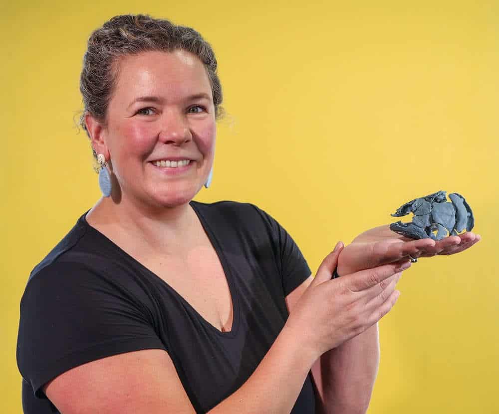Palaeontologist holding fossil skull on yellow background