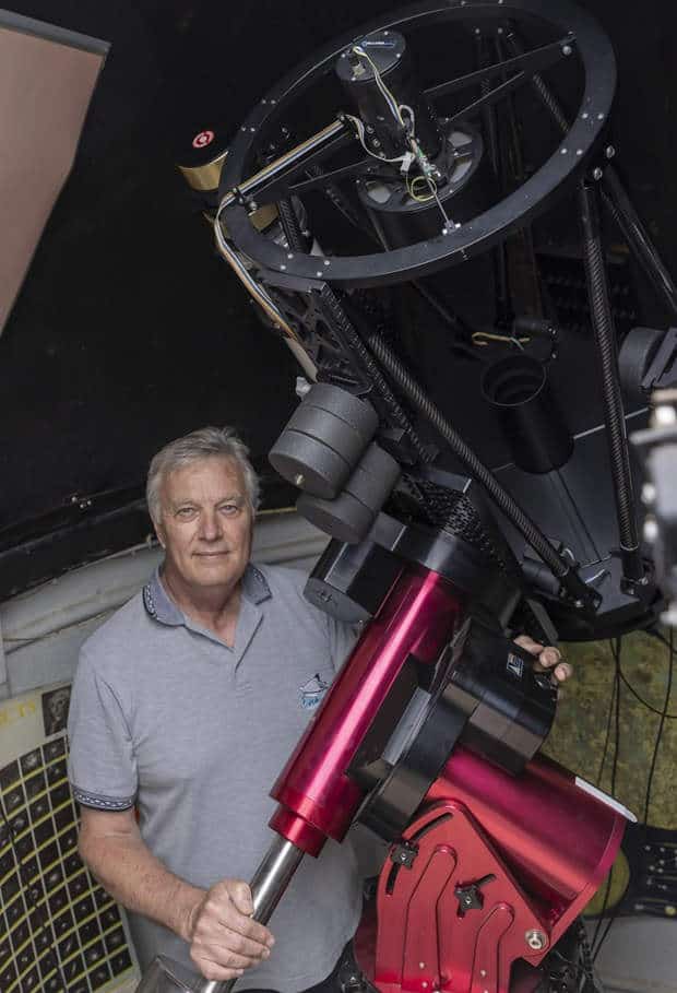 Man standing next to telescope in private observatory