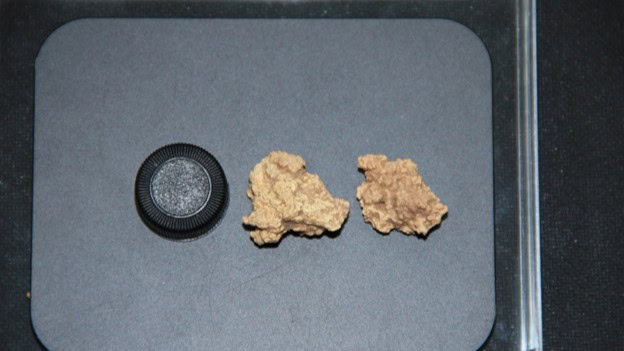 Two pieces of oldest ancient cheese next to bottle cap