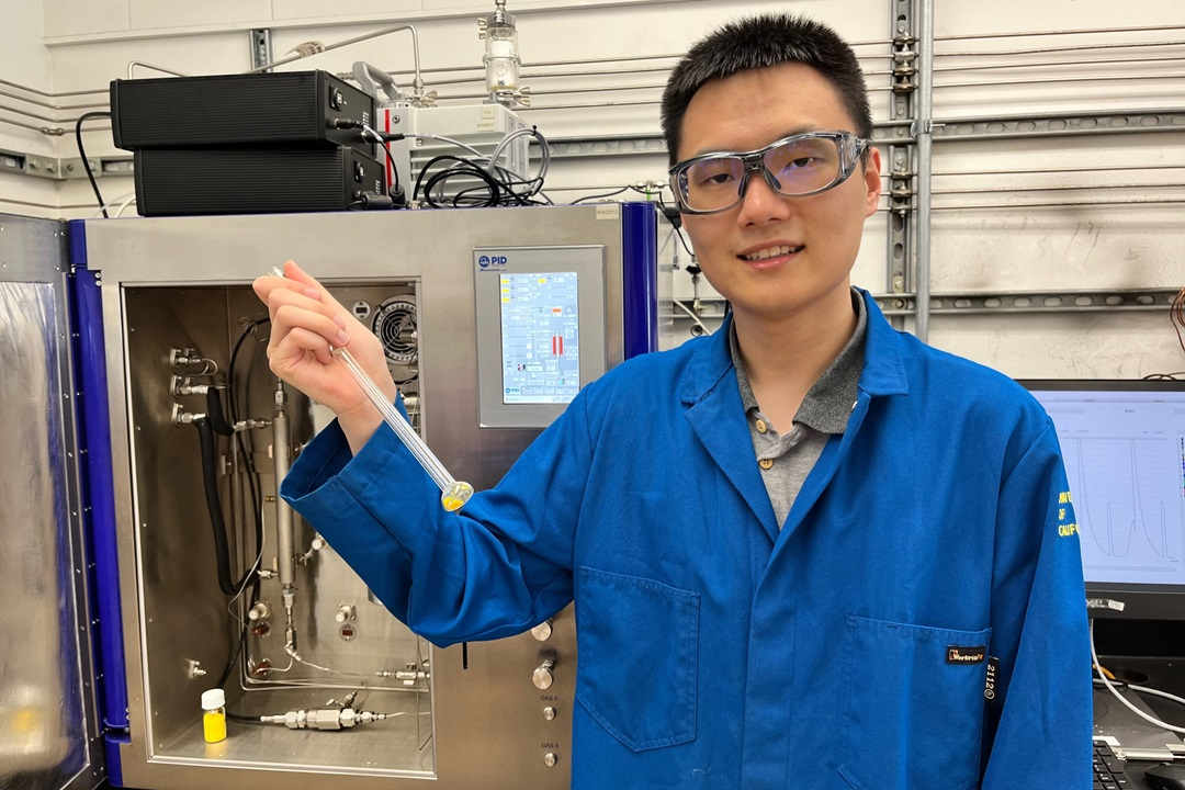 Student in blue lab coat holding test tube