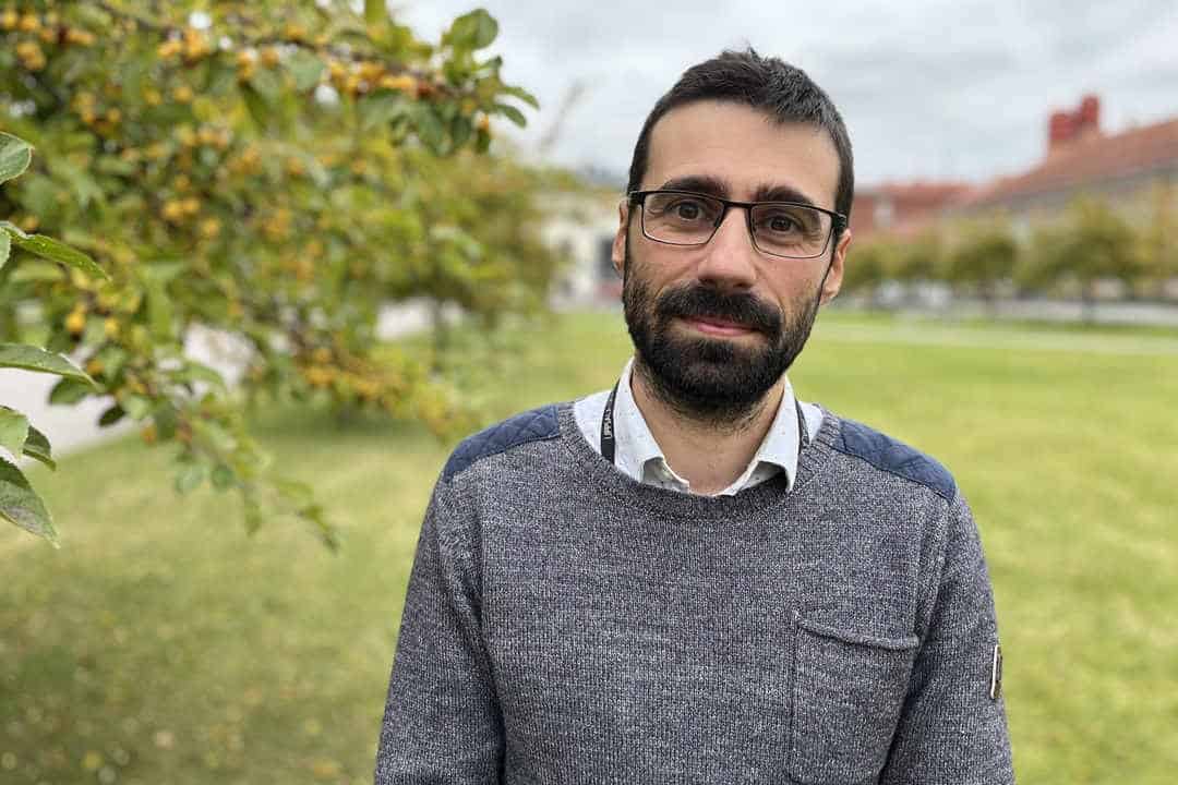 Scientist with beard and glasses in garden next to trees