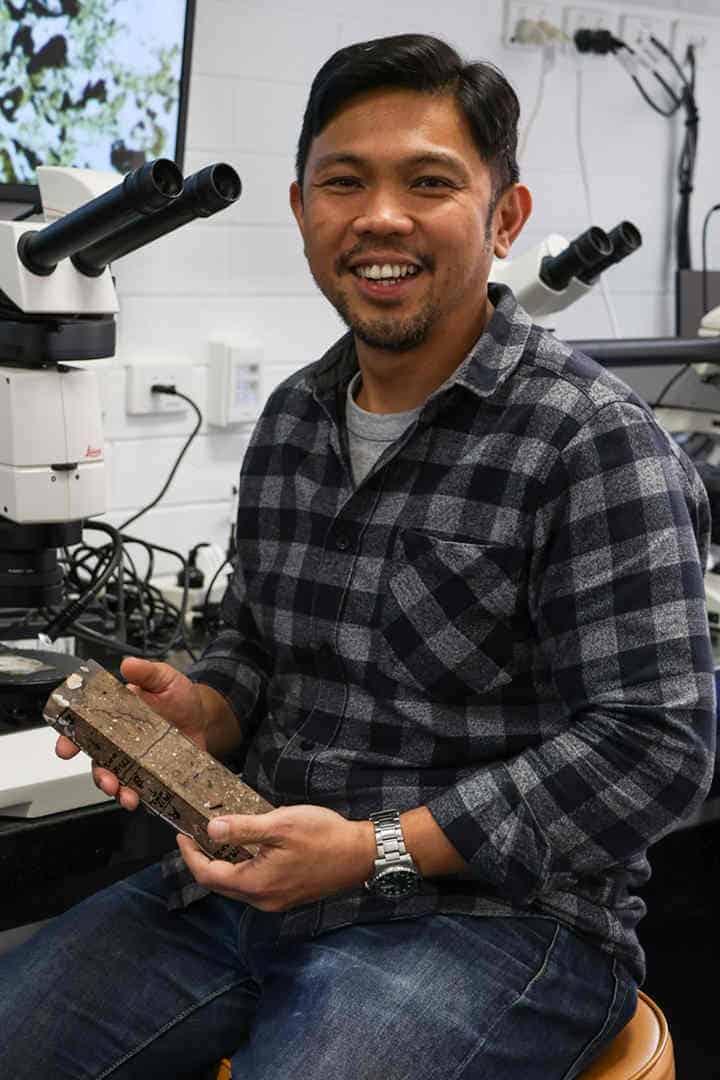 Archaeologist in lab with checkered shirt holding artefact