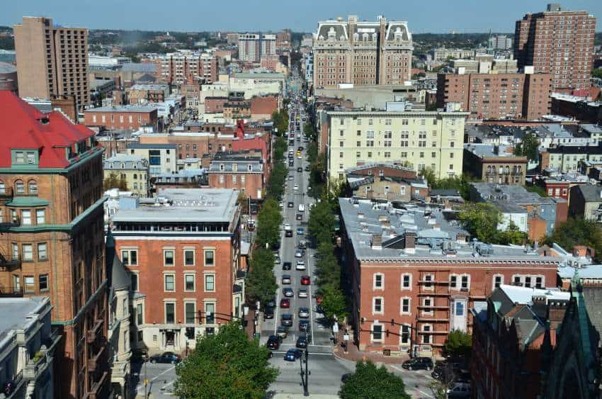 A photograph of an urban environment showing mid-height buildings and streets lined with green trees