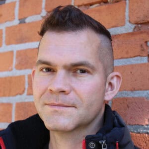 Man in front of brick wall.