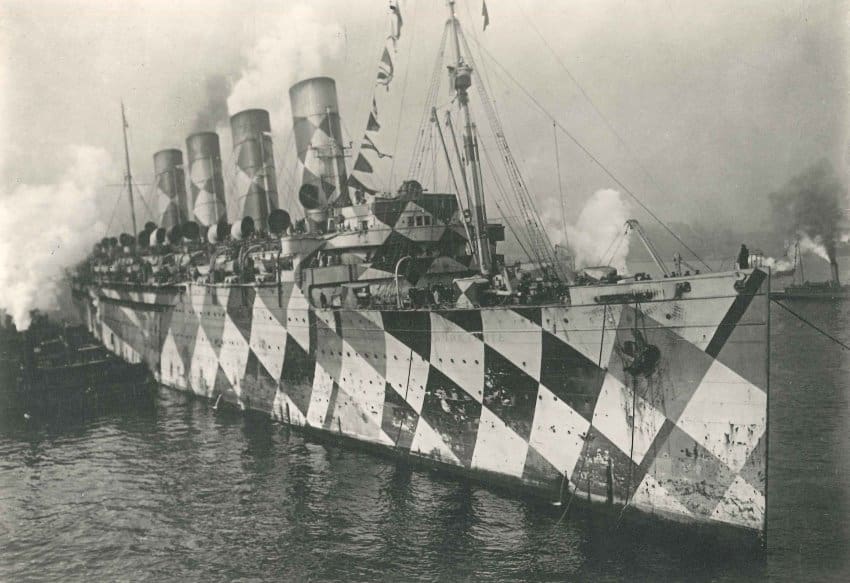 A black and white photograph of a large steam powered ship painted in an alternating checkered pattern