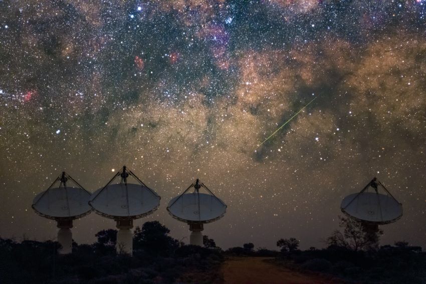 4 radio dishes pointed towards the night sky, which is covered in a blanket of stars