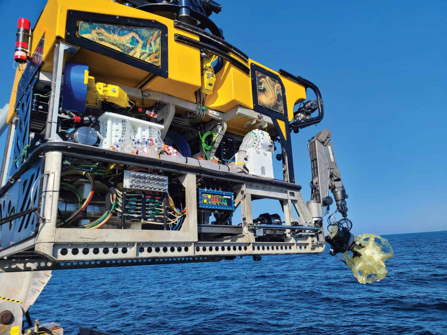 Yellow water vehicle holding a capsule at the front about to be lowered into the sea.