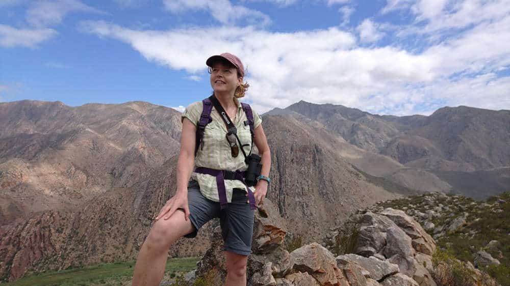 Woman palaeontologist on mountain under blue sky