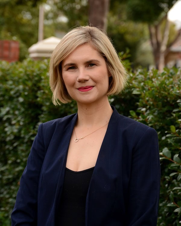 Woman scientist in front of hedge in blue blazer