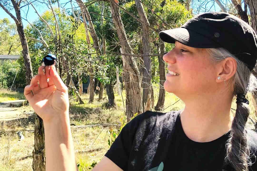 Woman in hat holding small bird