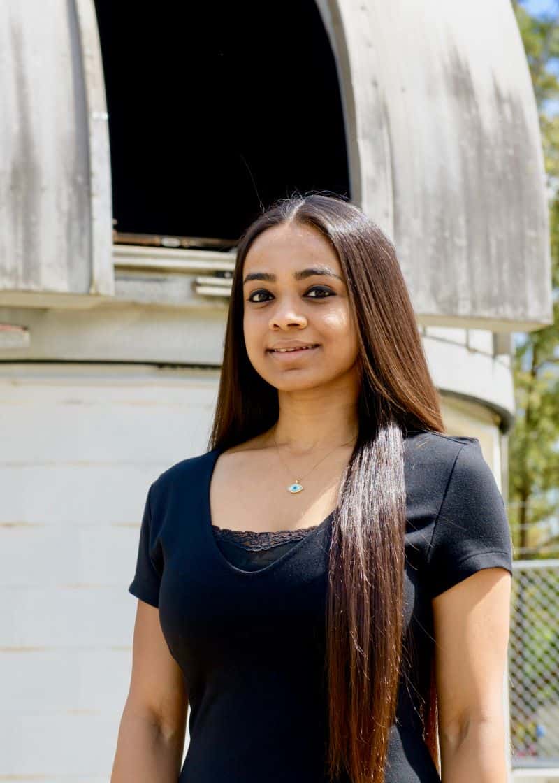 Scientist with long hair in front of astronomical observatory
