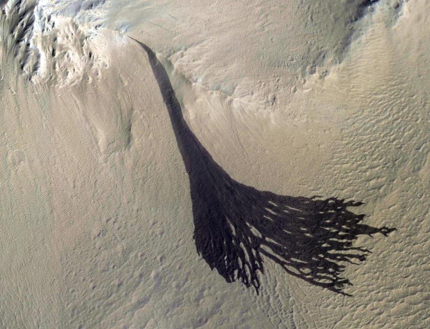 Dark black streak fans out at the bottom of a martian slope
