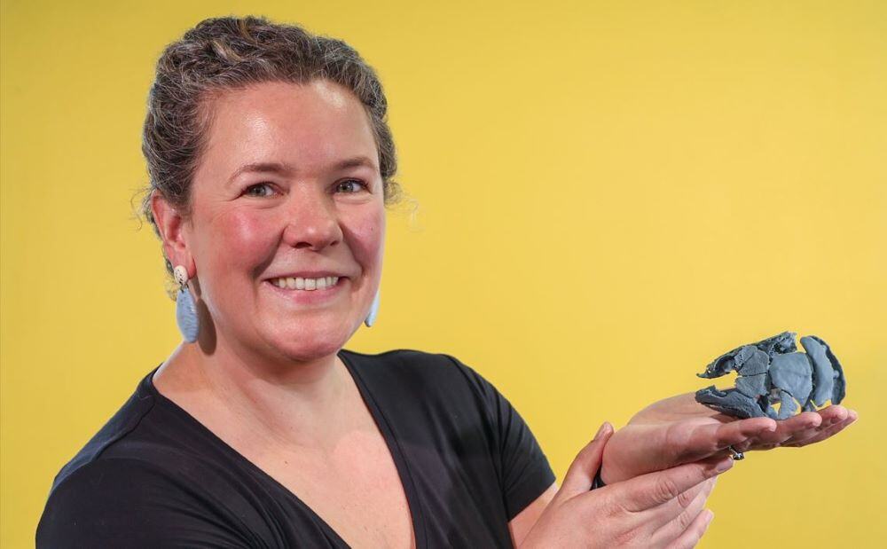 Woman holding fossil on yellow background