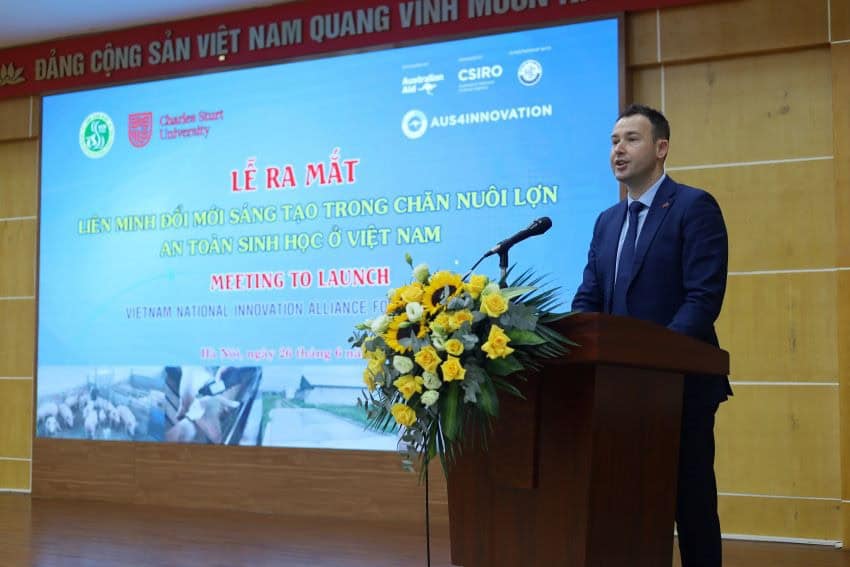 Man speaking at a lectern, words on the screen behind are in vietnamese and english "meeting to launch vietnamese national innovation allience.. "