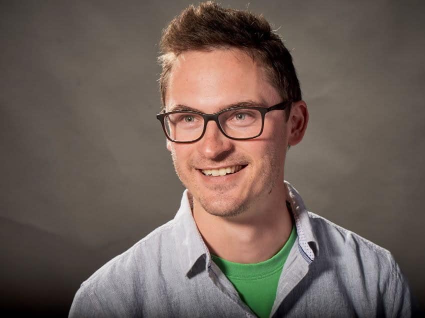 Headshot of man wearing glasses an green t-shirt and shirt with collar over.