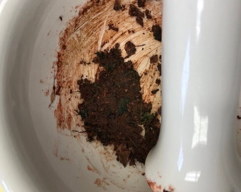 Red brown dirt like paste in white mortar and pestel