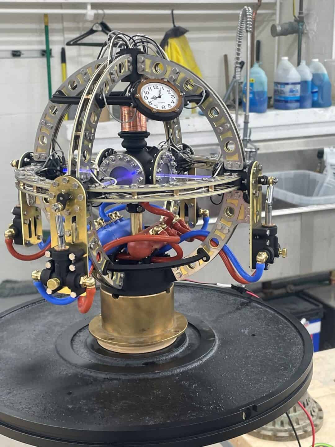Globe shaped machine with mechanical and electrical parts including an analogue clock face.