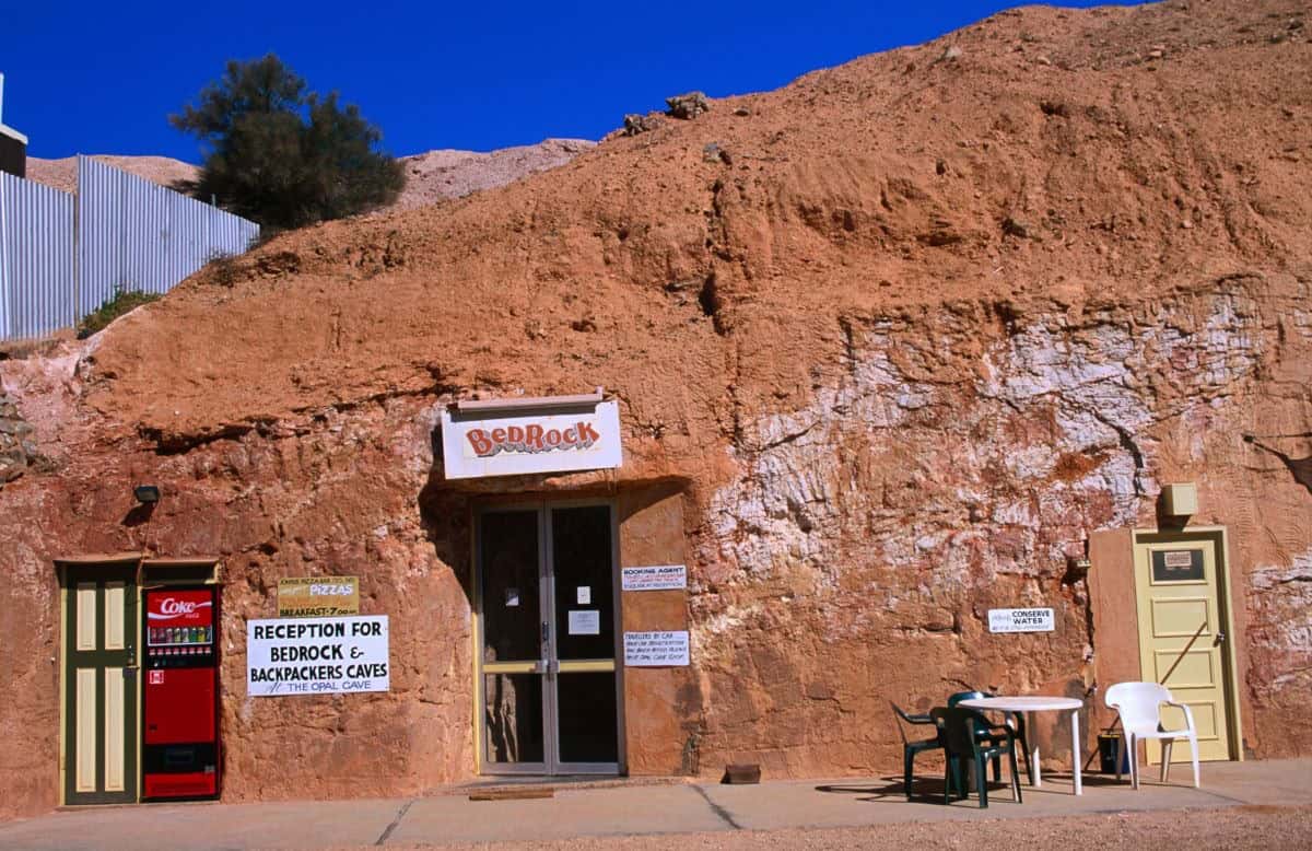 Several doorways cut into the red rock wall, sign above the door reads "bedrock".