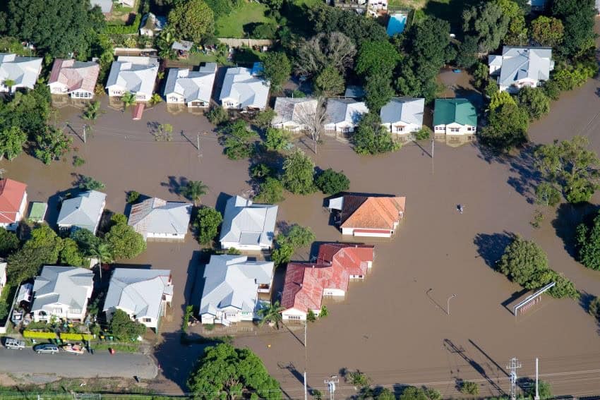 Arial view of houses underwater with just rooftops showing in the muddy water.