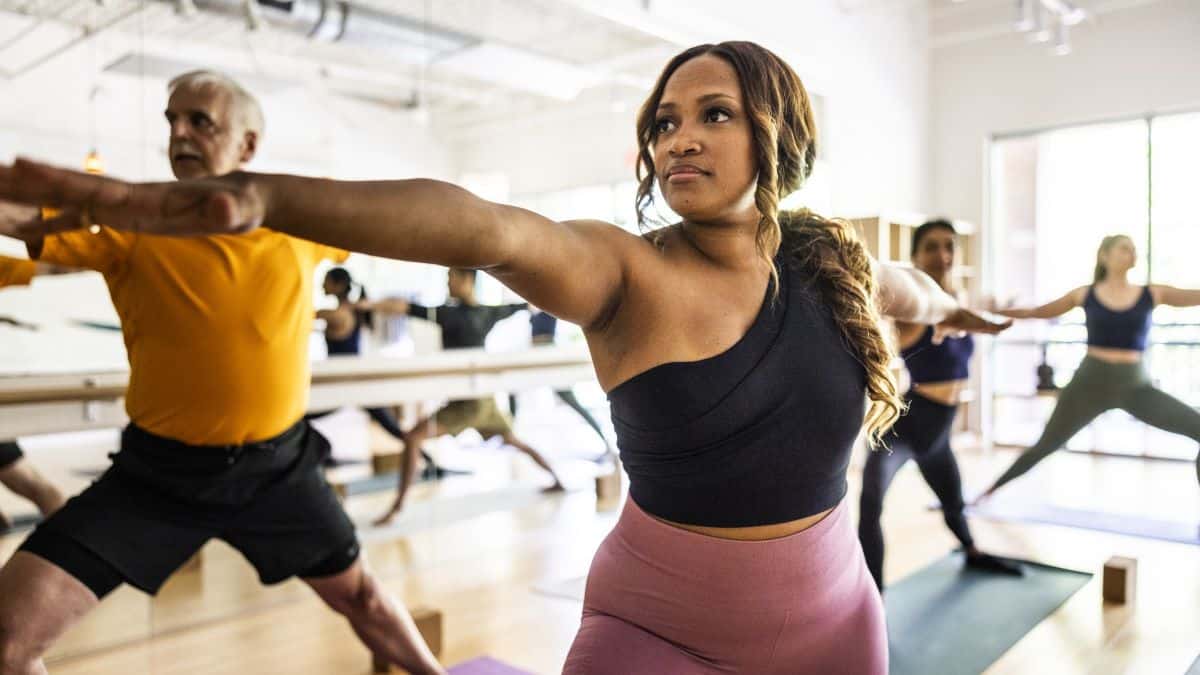 Diverse group of yoga students doing warrior pose in yoga class