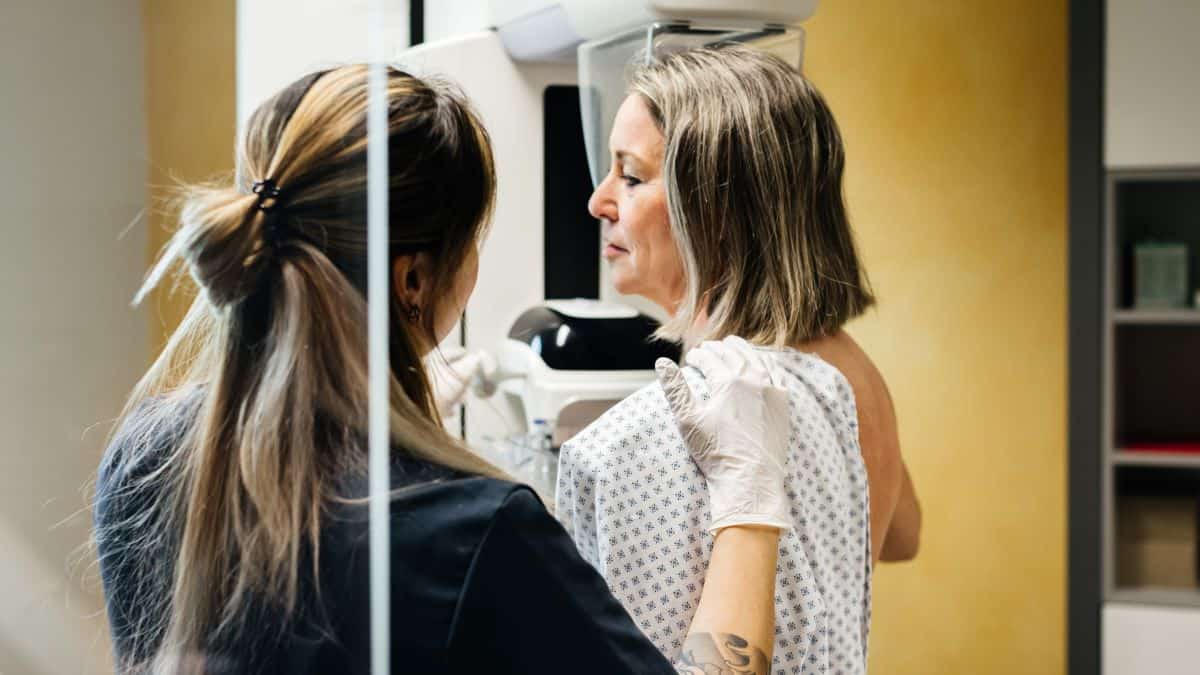 Nurse provides assistance to a patient undergoing a mammogram in a modern medical facility