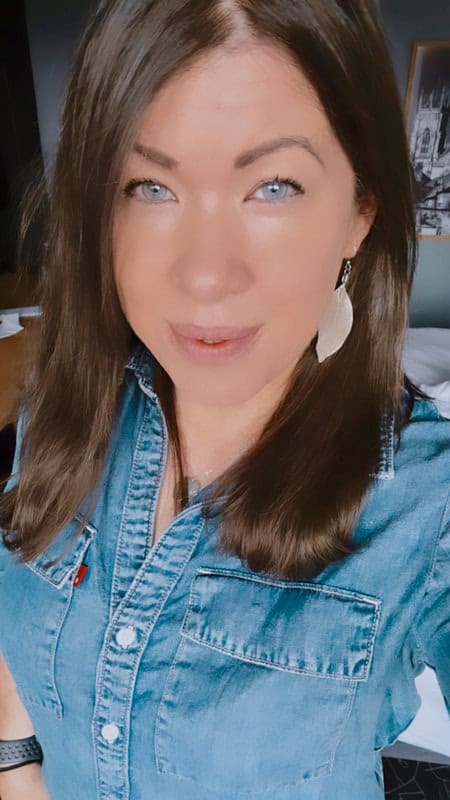 Woman with shoulder length brown hair, wearing a blue denim shirt.