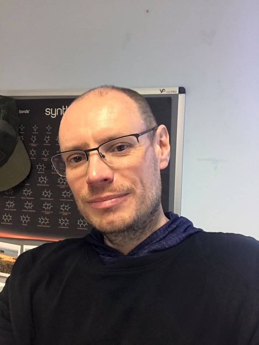Headshot of balding man wearing glasses and a dark jumper.