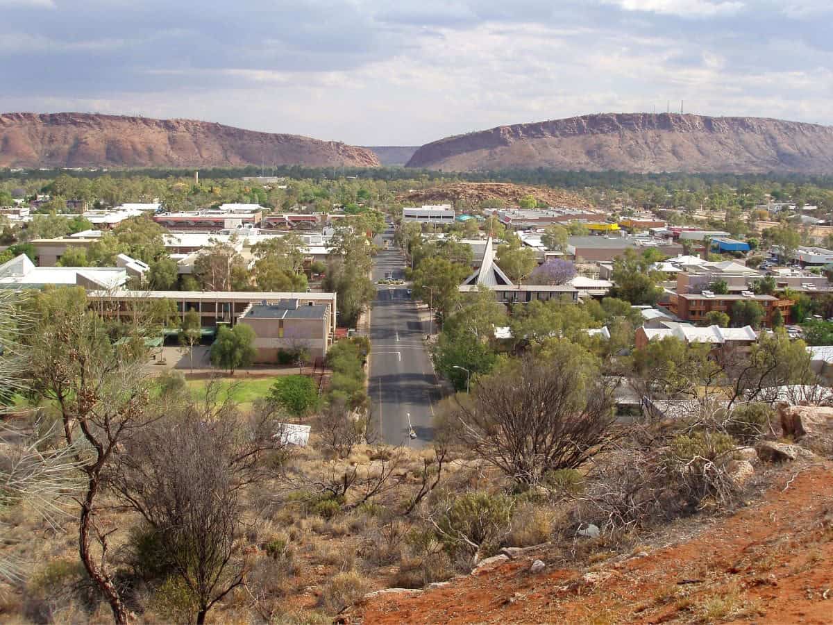 Town view from above, red rocky foreground and streets and buildings below.