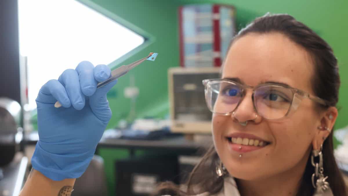Scientist with glasses and cool earrings holds small device with tweezers