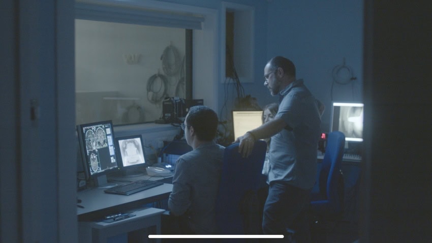 A group of researchers watch the results of an mri scan on an individual during a breathwork session