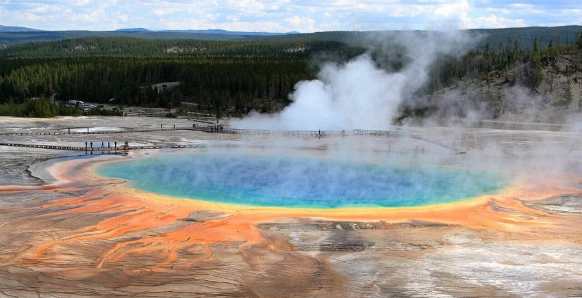 A steaming hotspring with blue, green water and yellow and orange deposits surrounding it