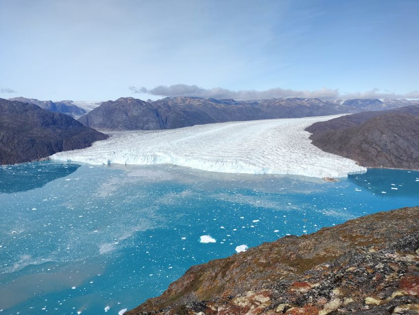 A glacier spilling out from greenland onto the ocean, breaking up into sea ice