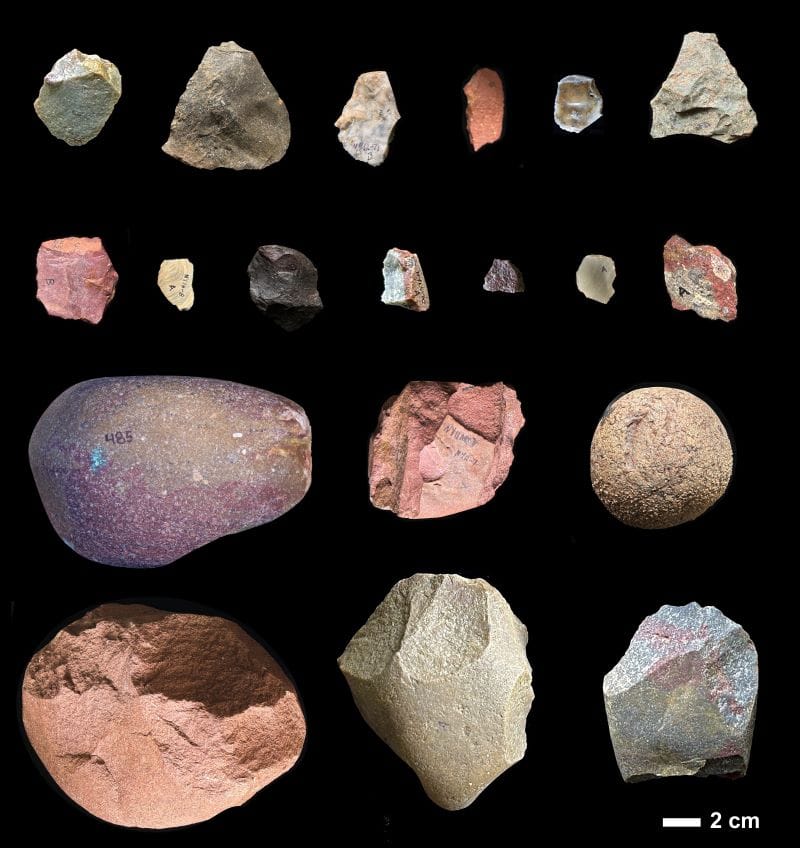 Array of ancient human stone tools on black background