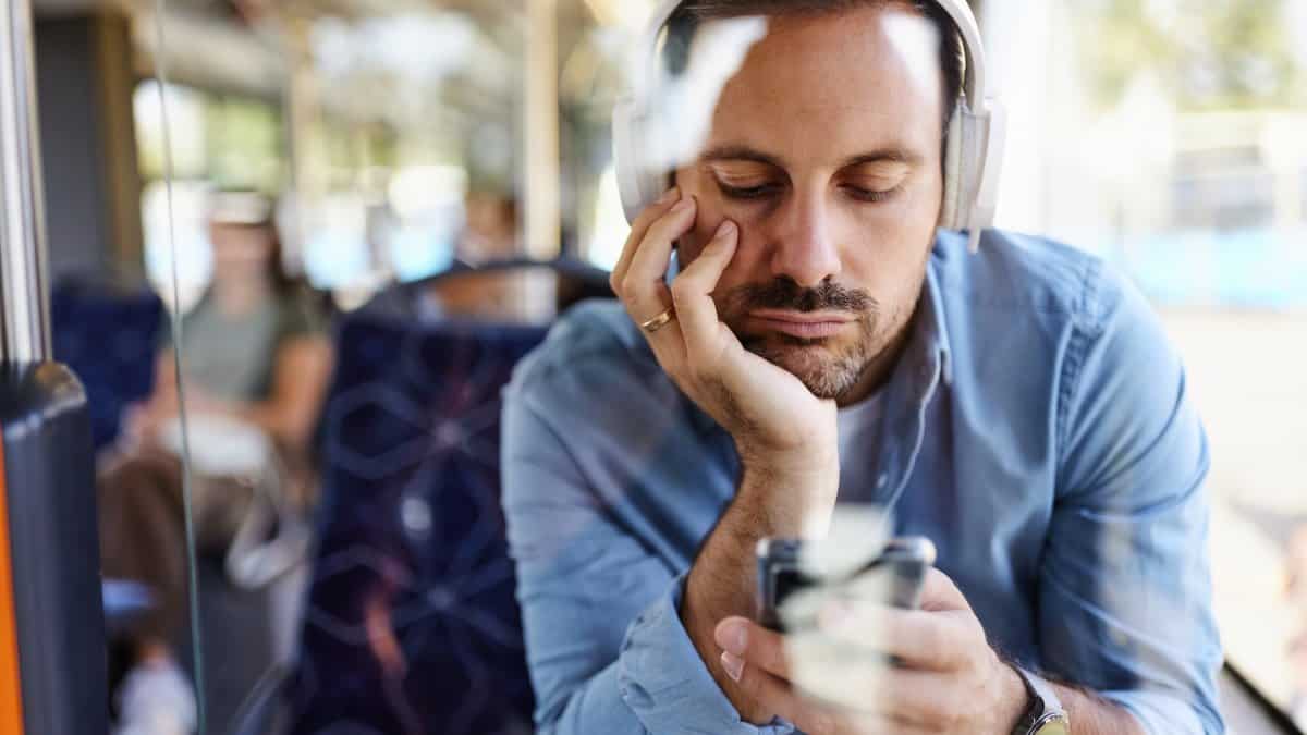 Bored man listening music over mobile phone in a bus