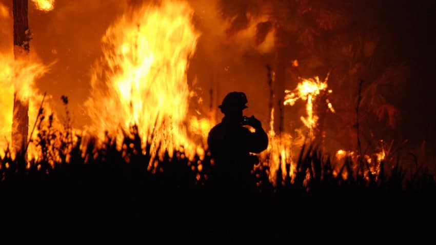 The silhouette of a firefighter in front of a raging wildfire
