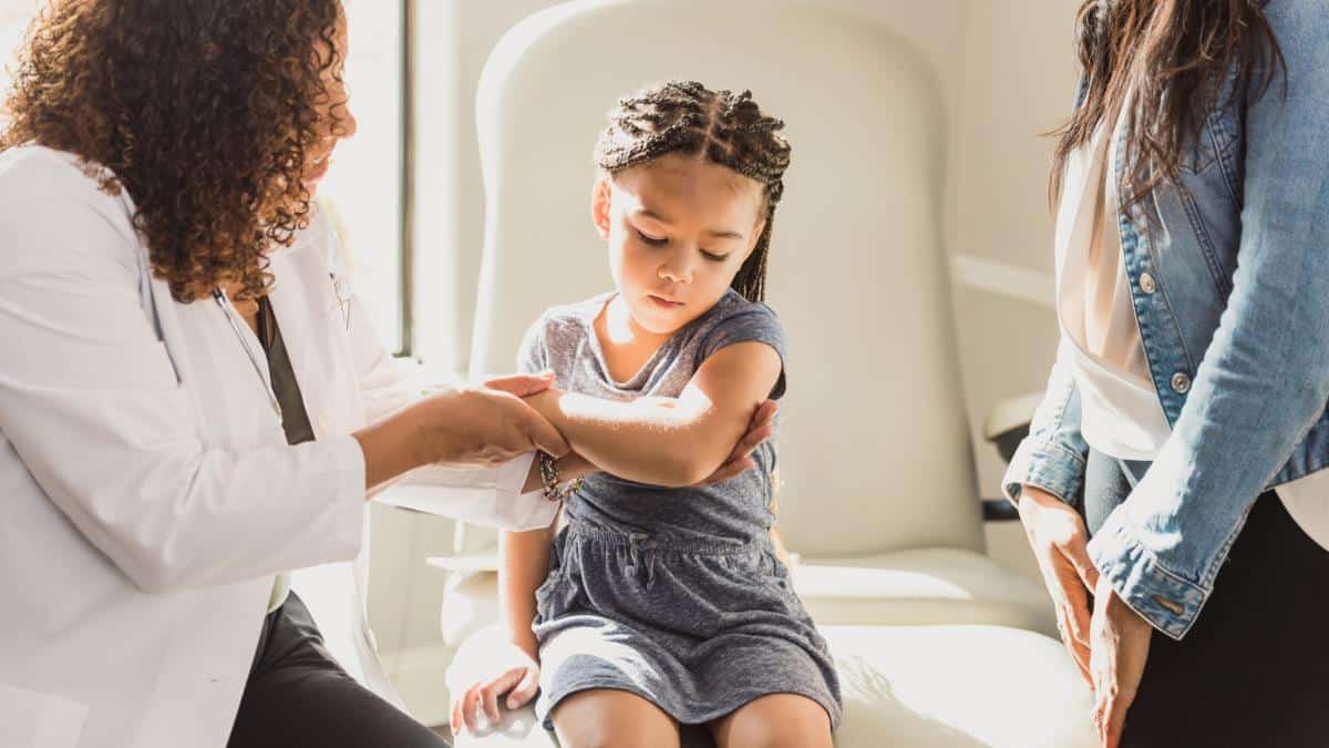 child in hospital bed being by physician