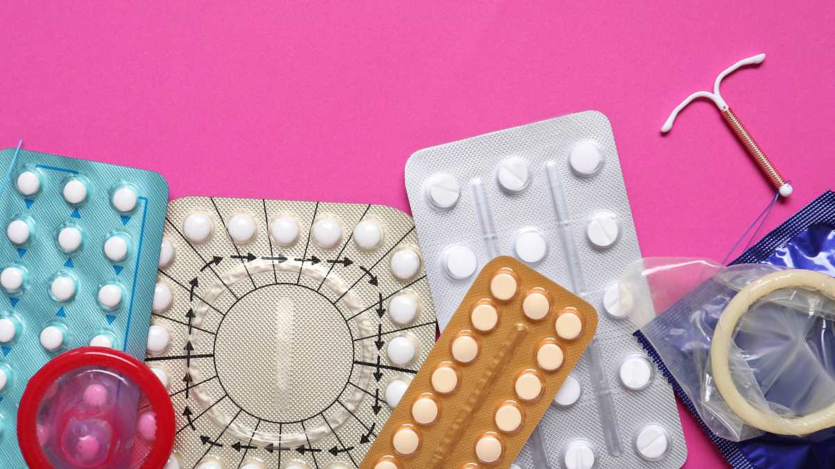 different contraception methods including pills, condoms and IUDs on pink background