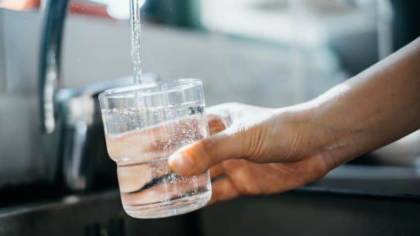 Hand filling glass with tap water