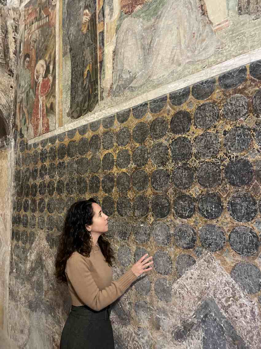 Person standing next to fresco examining it