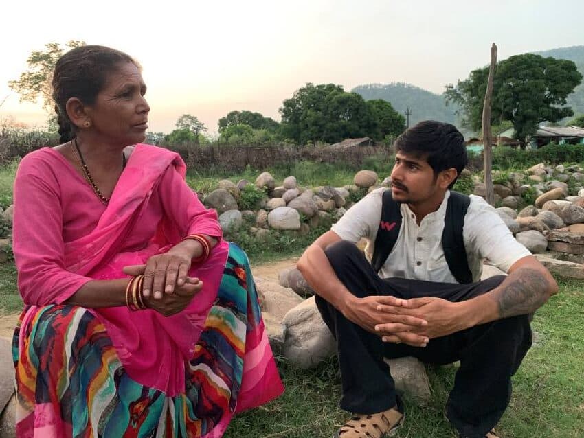 Two people sit on roadside talking