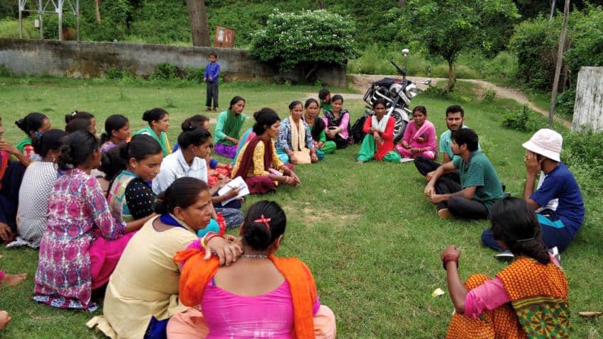 Group of approximately 20 people sitting on grass talking