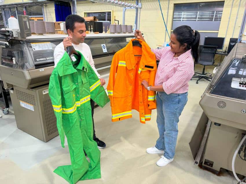 Two people in lab holding firefighting clothes