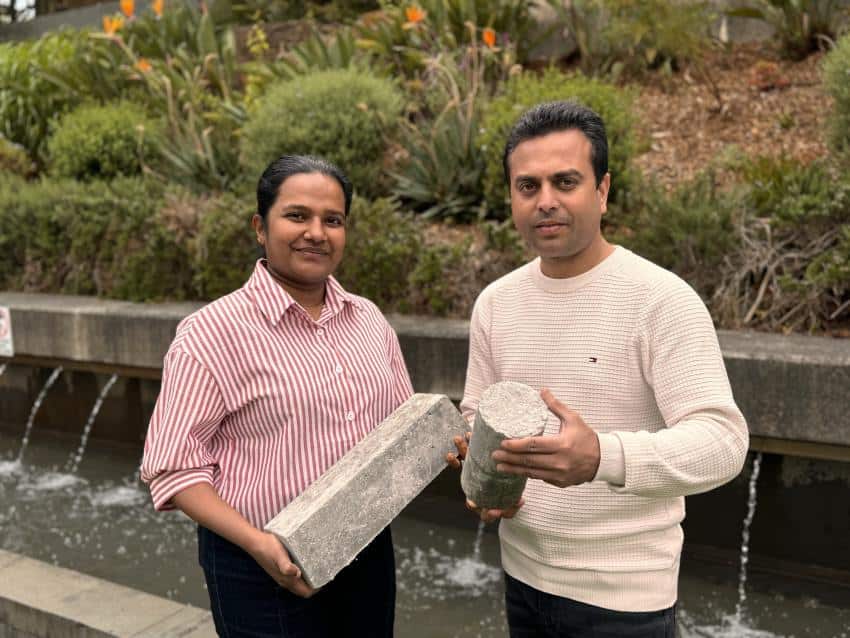 Two people standing outside holding concrete samples