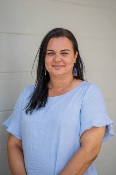 Woman with dangly earrings and pale blue top.