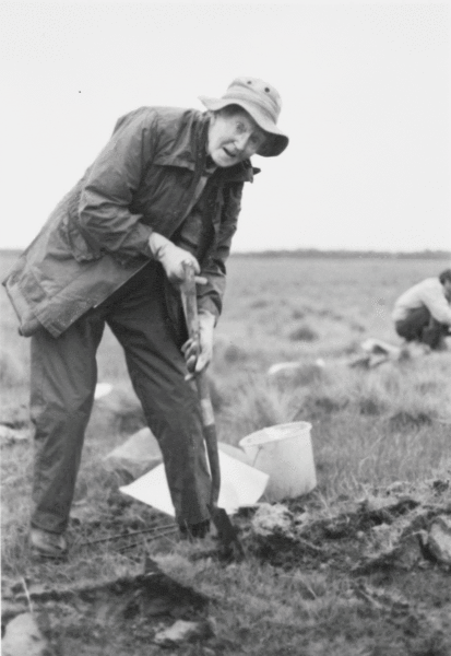 Black and white photo of a woman digging in a field.